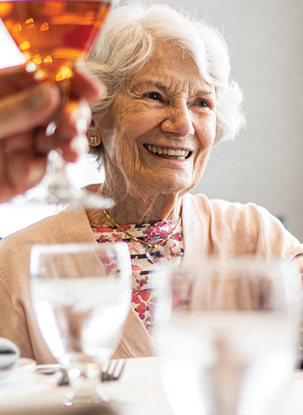 A happy and confident senior, raising a glass at Don Mills Retirement Residence